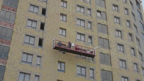 Workers in the construction cradle make cladding Stock Footage 132494100