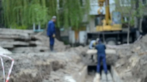 Workers with construction crane cover new water pipes with concrete slabs Stock Footage 106406035