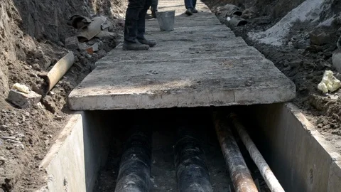 Workers with construction crane cover new water pipes with concrete slabs Stock Footage 107184914