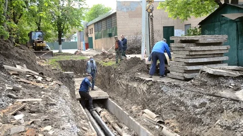 Workers with construction crane cover new water pipes with concrete slabs Stock Footage 128190179