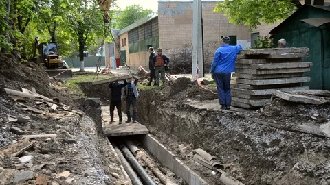Workers with construction crane cover new water pipes with concrete slabs Stock Footage 128191472