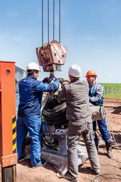 Workers at a construction site hook a load to the hook of a construction crane Stock Photos