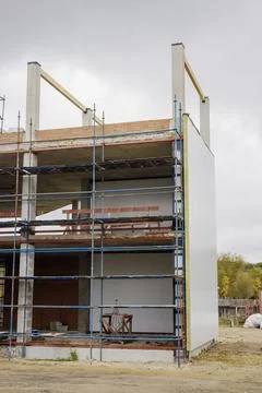 Workers continue construction of a building with scaffolding around it. The s Stock Photos