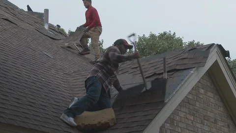 Workers continue removing damaged shingles from the roof of a city home, 4K. Stock Footage 116097303