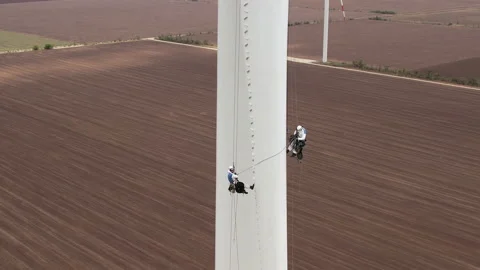 Workers couple repairs wind driven turbine near plowed field Stock Footage 165203929