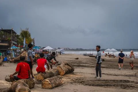 Workers Cutting Logs on a Tropical Beach in Bali Stock Photos