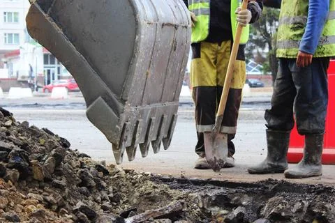 Workers deepen the road pit with an excavator for further repairs and asph... Stock Photos