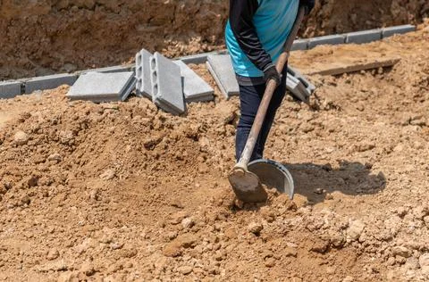 Workers dig the soil to adjust the construction area. Stock Photos
