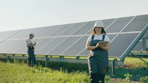 Workers with digital tablets wearing safety helmets on a solar panel farm. Stock Footage 251564979