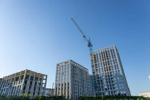 Workers diligently construct new buildings, with cranes lifting materials a.. Stock Photos
