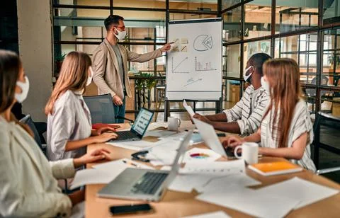 Workers discuss and meet while wearing a medical mask to protect against the Stock Photos