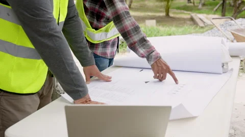 Workers discuss construction big house plan paper on white table outdoor. Stock Footage 257442696