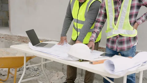 Workers discuss plan in on-site construction. Asian engineers in yellow Stock Footage 257443003
