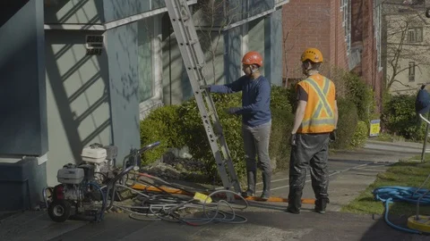 Workers discussing on a project by condo building. Stockbeeldmateriaal 128197000