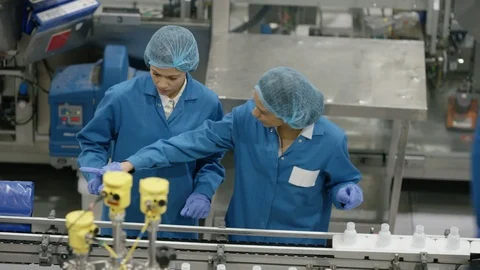Workers discussing while inspecting cosmetic bottles on production line Video stock 107968699