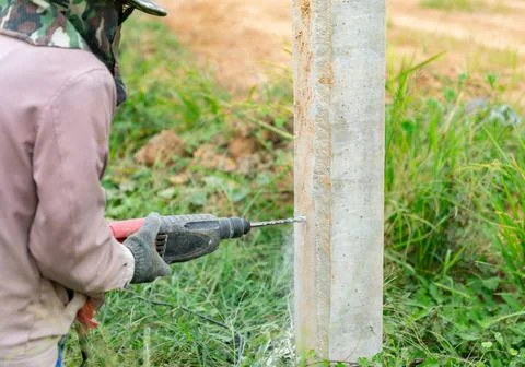 Workers drill cement columns to install support metal sheet. Stock Photos