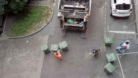 Workers empty two bins into garbage truck. Overhead view. Video stock 132506894