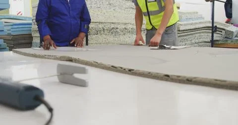 Workers examine material on a large table in an industrial setting Stock Photos