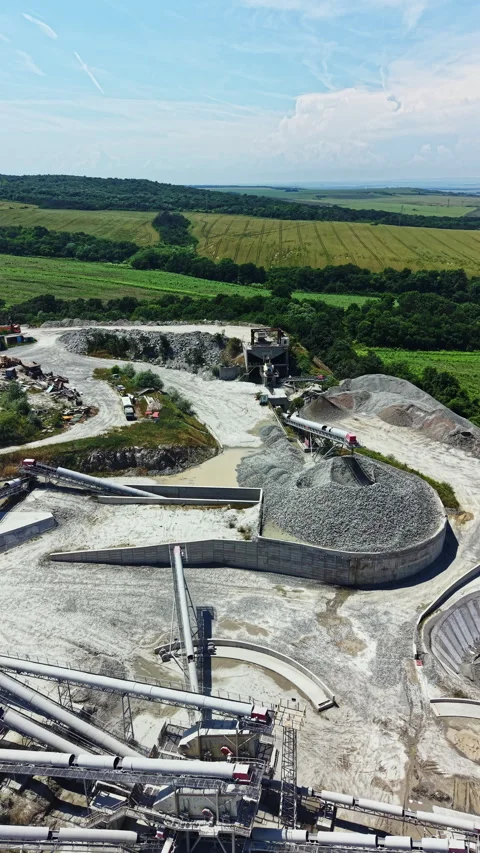 Workers extract granite from a large quarry surrounded by green fields under a Stock Footage 337944384