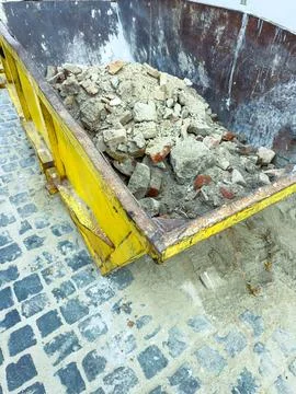 Workers filled a yellow dumpster with bricks and concrete rubble on a cobbles Stock Photos