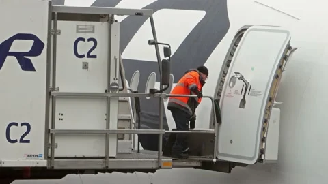 Workers finish loading an airliner at the snowy Helsinki Airport, Finland Stock Footage 220048424