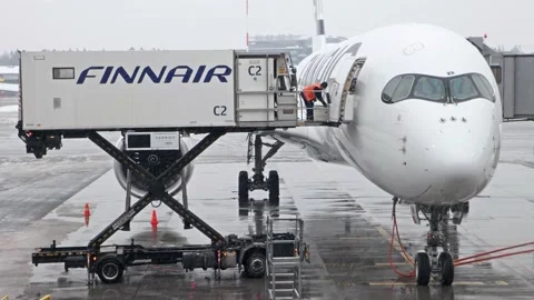 Workers finish loading an airliner at the snowy Helsinki Airport, Finland Stock Footage 233230385