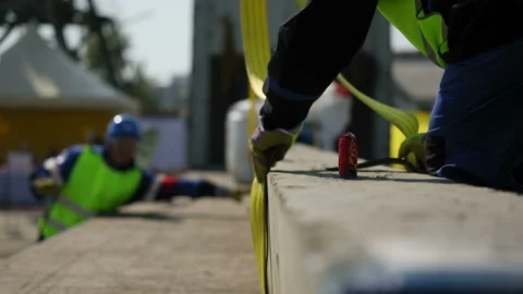 Workers fix belts on a concrete beam and give a signal to the crane operator Stock-Footage 93294594