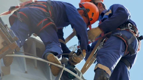 Workers fix equipment on electric tower against blue sky Stock Footage 92718876