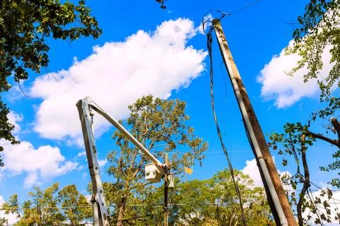 Workers fix power lines after hurricane under blue sky in residential area Stock Photos