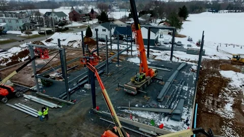 Workers gather at a construction site in a cold winter setting. Orange cranes Stock Footage 336115383