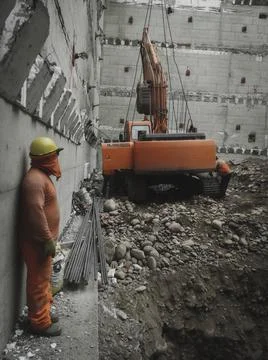 Workers girdling an excavator to remove it from the site and a worker looking Stock Photos