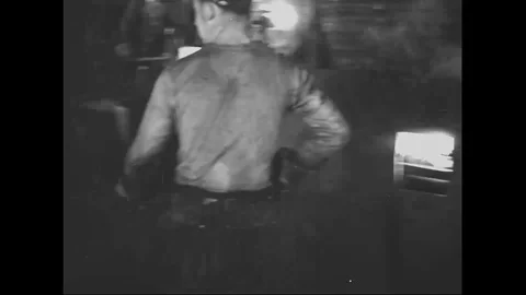 Workers gives shape to hot metal plate under hammering machine - 1939 Stock Footage 101983209