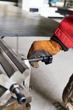 Worker's gloved hand on the adjusting screw of a bending machine Stock Photos