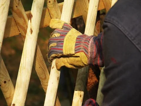 Worker’s gloved hand assembling wooden fence outdoors Stock Photos