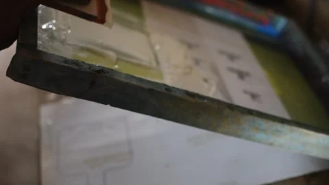 A worker’s hand applying ink on a screen printing frame 動画素材 326930889