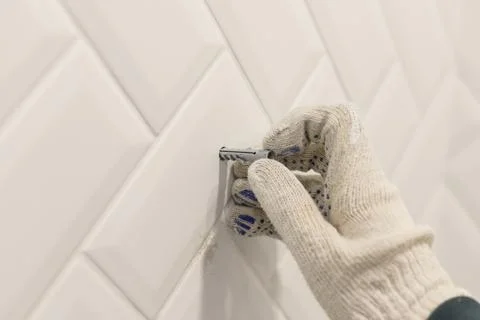Worker's hand in glove inserts wall pvc dowel in wall cladded with tile ceramic Stock Photos