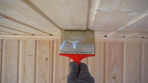 Worker’s hand holds a brush and paints a wooden wall, wall cladding, floor or wa Video stock 98004418