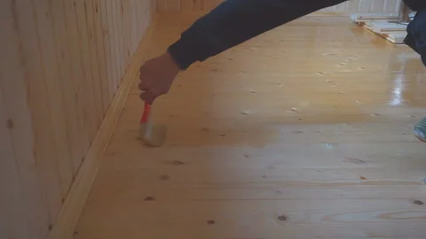 Worker’s hand holds a brush and paints a wooden wall, wall cladding, floor or wa Stock Footage 98004500