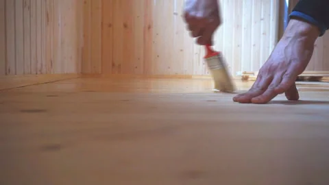 Worker’s hand holds a brush and paints a wooden wall, wall cladding, floor or wa Stock Footage 98004503