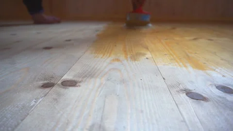 Worker’s hand holds a brush and paints a wooden wall, wall cladding, floor or wa Stock Footage 98004568