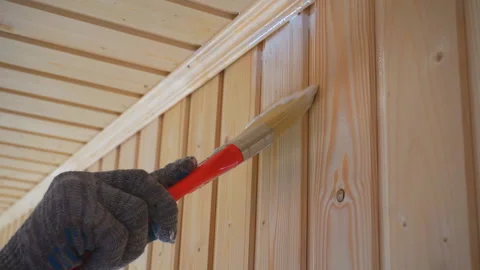 Worker’s hand holds a brush and paints a wooden wall, wall cladding, floor or wa Stock Footage 98004587