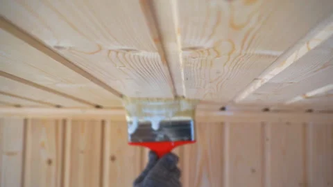 Worker’s hand holds a brush and paints a wooden wall, wall cladding, floor or wa Video stock 98004727