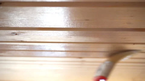 Worker’s hand holds a brush and paints a wooden wall, wall cladding, floor or wa Stock Footage 98004813