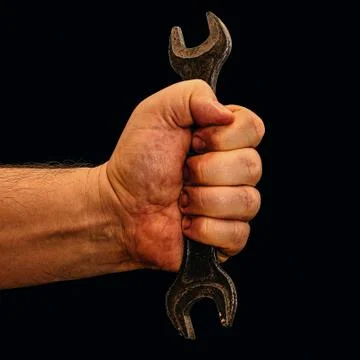 Worker's hand with open-end wrench isolated on black Stock Photos