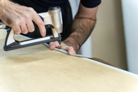 Worker's hand operates a blue pneumatic stapler. Stock Photos
