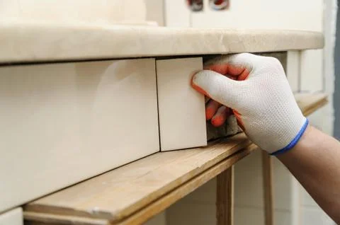 Worker's hand puts the piece of tile. Stock Photos