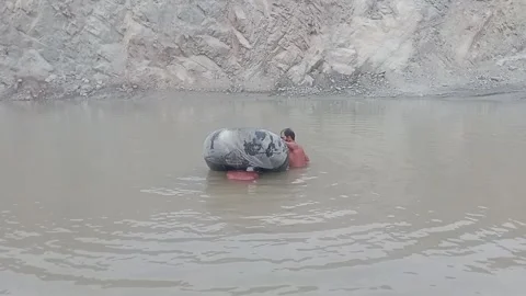 Workers Handling Tire in Quarry Pond, Sargodha, Pakistan - August 30, 2026 Video stock 344046506
