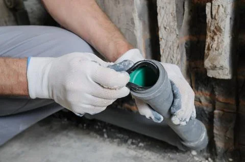 Worker's hands are installing sewer pipes. Stock Photos