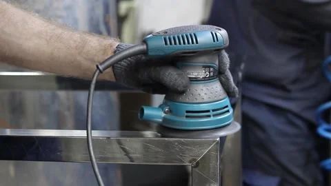 Worker's hands in gray cloth gloves use a metal grinder to process a metal part Stock Footage 133449631