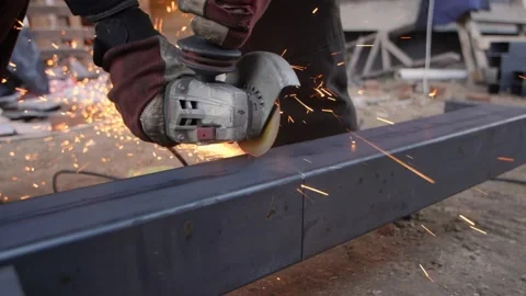A worker's hands hold a working angle grinder cutting metal. Stock Footage 230982501